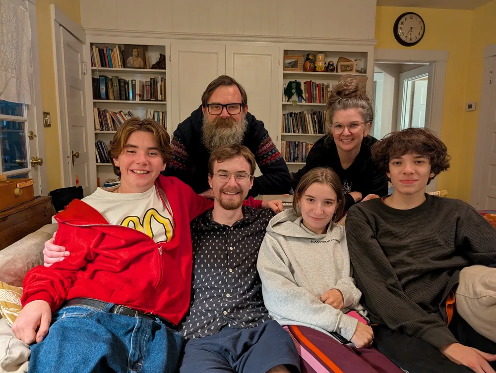 Ben with Jen and their four kids, all smiling together in front of a wall of bookshelves