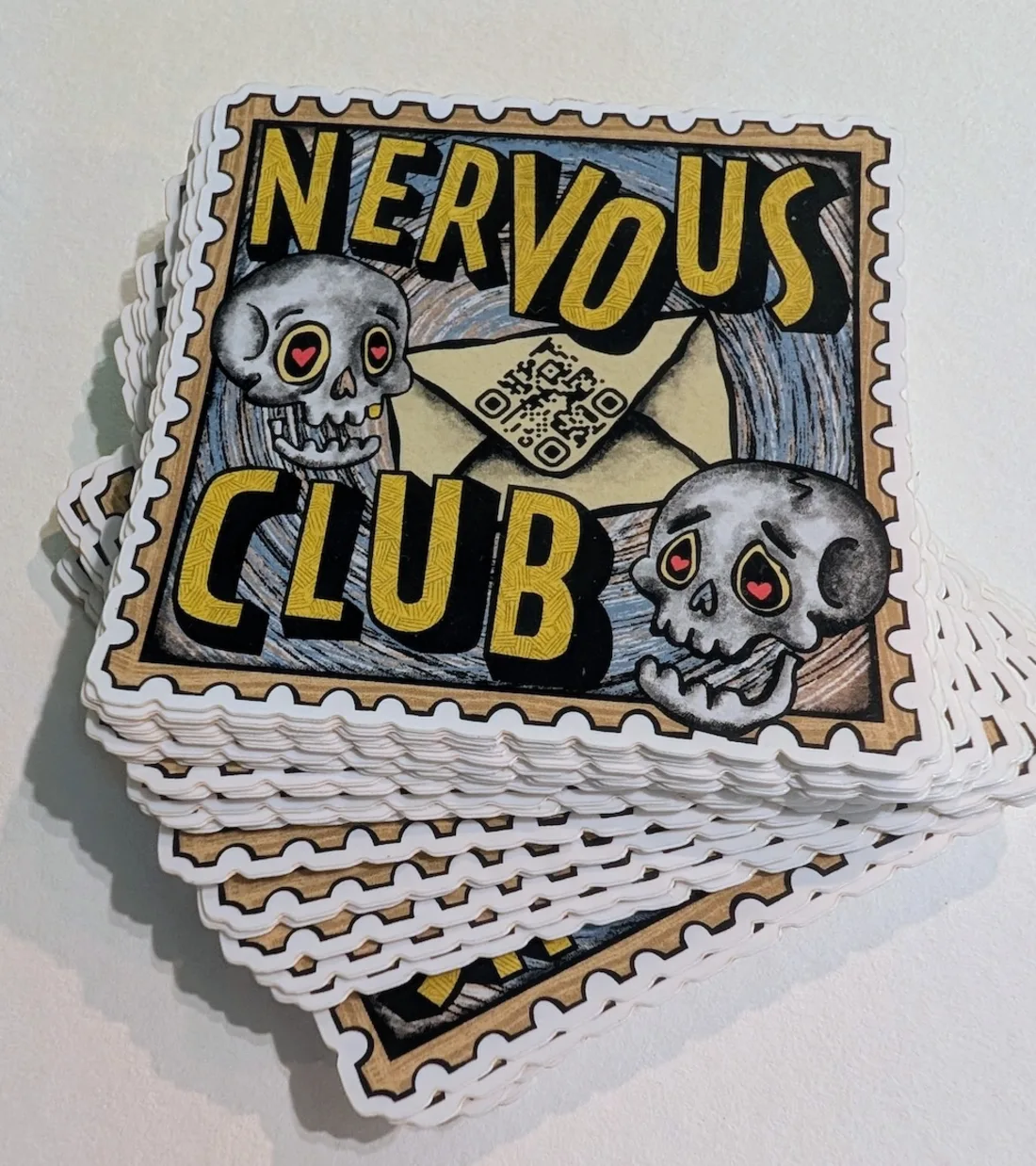A stack of die-cut Nervous Club stamp stickers — skulls and an envelope with a QR code